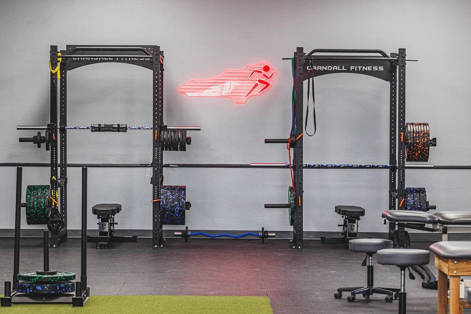 Back in Action Therapy clinic gym with squat racks and BIA neon sign